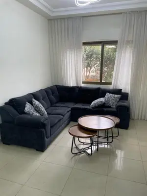 a living room with a blue couch and a table at Charming modern 2BD in Abdoun in Amman