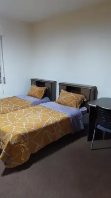 a bedroom with two beds and a table with a chair at شقة مفروشة مجهزة بكل الخدمات in Irbid