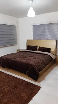a bedroom with a bed with a brown comforter at شقة مفروشة مجهزة بكل الخدمات in Irbid