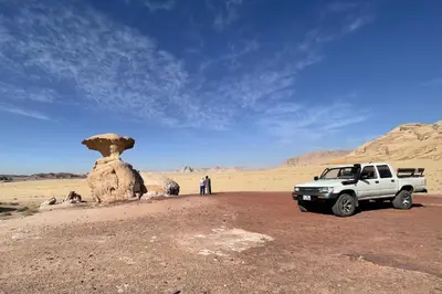 a white truck parked in the desert near a rock formation at Ahmad and Fatima's Traditional Bedouin Camp in Wadi Rum