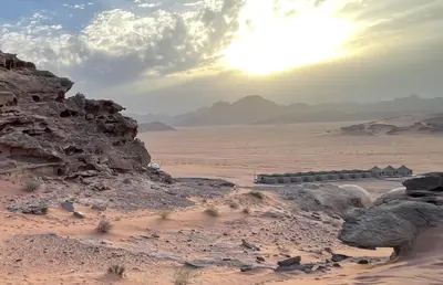 a view of a desert with the sun in the background at Ahmad and Fatima's Traditional Bedouin Camp in Wadi Rum