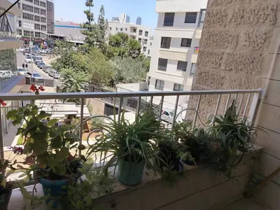 a balcony with potted plants on a city street at شقة مفروشة الدوار السابع خلف كوزمو in Amman