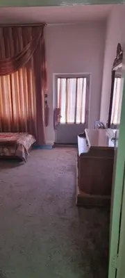 a bedroom with a bed and a desk and two windows at Nights of the Orient Guesthouse in Al Salt