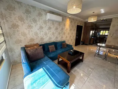 a living room with a blue couch and a table at Cozy apt Grt location for long and short stay in Amman