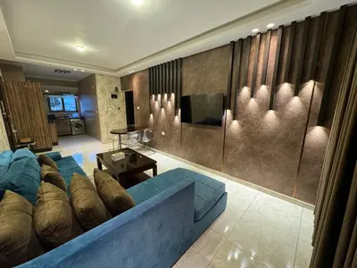 a living room with a blue couch and a television at Cozy apt Grt location for long and short stay in Amman