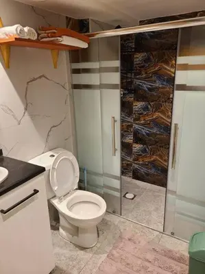 a bathroom with a toilet and a glass shower at Loft Apartment Jabal Amman B in Amman