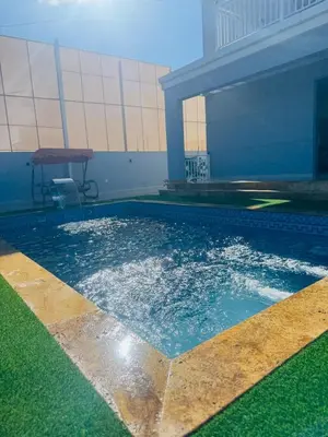a swimming pool with blue water and a table at منتجع الحور in Ajloun
