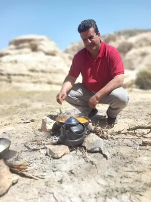 a man is cooking food over a camp fire at Al -Nawatef Eco Lodge- Dana Nature Reserve in Dana