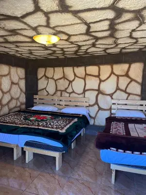 two beds in a room with a stone wall at Al -Nawatef Eco Lodge- Dana Nature Reserve in Dana