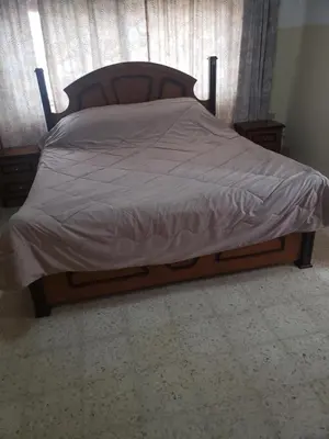 a bed with a wooden frame with a gray comforter at Alotaibi bulding in Amman