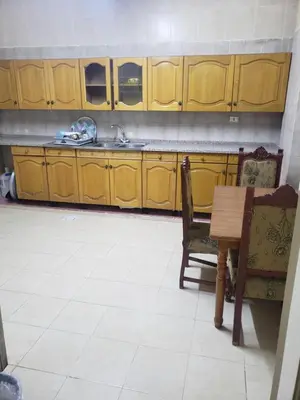 a kitchen with wooden cabinets and a table and a sink at ALOTAIBI bulding # 6 in Amman