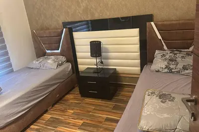 a room with two beds and a lamp on a night stand at Apartment in Amman 7'th Circle in Amman