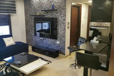 a living room with a blue couch and a tv at Apartment in Amman 7'th Circle in Amman