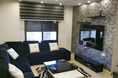 a living room with a blue couch and a tv at Apartment in Amman 7'th Circle in Amman