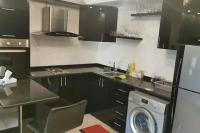 a kitchen with black cabinets and a washing machine at Apartment in Amman 7'th Circle in Amman