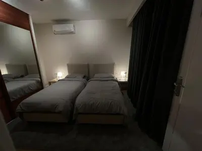 two beds in a small room with two lamps at Amman Central Cozy Apartment in Amman
