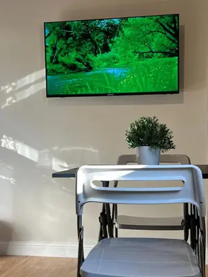 a table with a chair and a tv on a wall at Amman Central Cozy Apartment in Amman