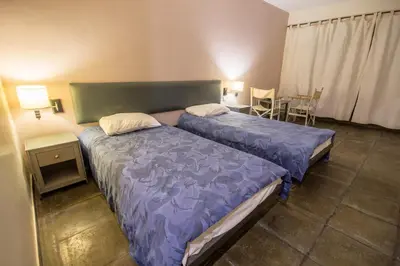 a bedroom with two beds and a table and chairs at Azraq Lodge in Al Azraq ash Shamālī