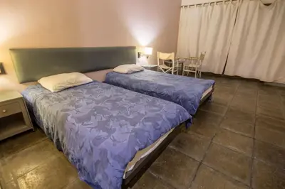 two beds in a room with a table and chairs at Azraq Lodge in Al Azraq ash Shamālī