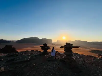 a woman standing on top of a mountain at sunset at Emad wadi rum camp in Wadi Rum