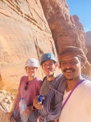 three people wearing helmets posing for a picture in the desert at Emad wadi rum camp in Wadi Rum