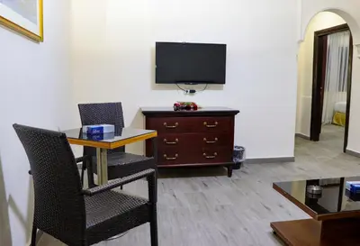 a living room with a table and a tv on a wall at Al Jamal Suites in Amman