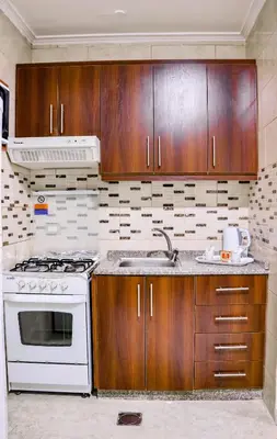 a kitchen with wooden cabinets and a white stove top oven at Al Jamal Suites in Amman