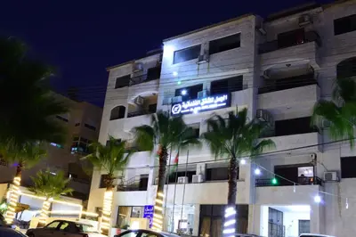 a hotel with a sign on the side of a building at Al Jamal Suites in Amman