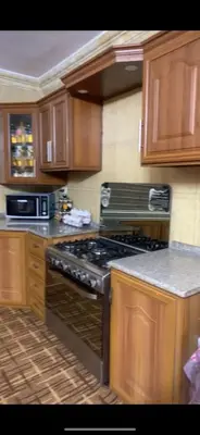 a kitchen with wooden cabinets and a stove top oven at Jordan in Irbid