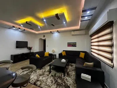 a living room with a couch and a tv at 5-New and Spacious Apartments Close to Market in Rujm ash Sharāʼirah