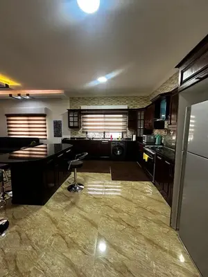a large kitchen with a counter and a refrigerator at 5-New and Spacious Apartments Close to Market in Rujm ash Sharāʼirah