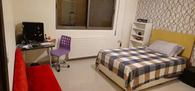 a bedroom with a bed and a desk and a computer at Luxuries Furnished Apartment in Shmeisani in Amman