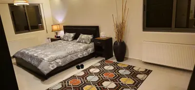 a bedroom with a bed and a rug at Luxuries Furnished Apartment in Shmeisani in Amman