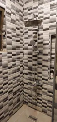 a shower in a bathroom with a tile wall at Luxuries Furnished Apartment in Shmeisani in Amman