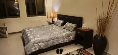 a bedroom with a bed and a night stand with a lamp at Luxuries Furnished Apartment in Shmeisani in Amman