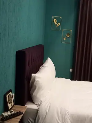 a bedroom with a white bed with a green wall at Blue Stone H in Madaba