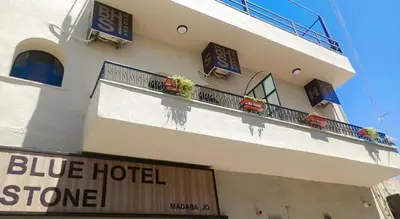 a white building with a blue hotel sign on it at Blue Stone H in Madaba