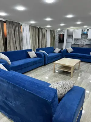 a living room with blue couches and a coffee table at Golden Horse Chalet And Club in Maḩaţţat al Jīzah