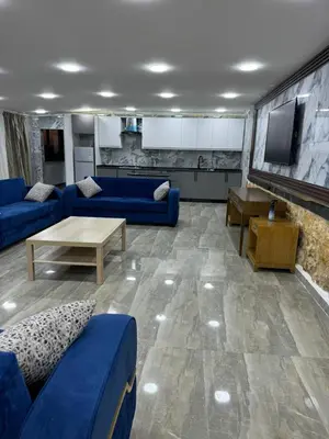a living room with blue couches and a tv at Golden Horse Chalet And Club in Maḩaţţat al Jīzah