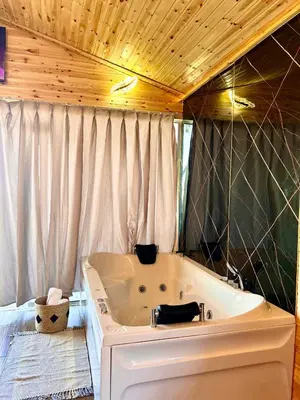 a bath tub in a bathroom with a wooden ceiling at اكواخ سفاري السياحية in Ajloun