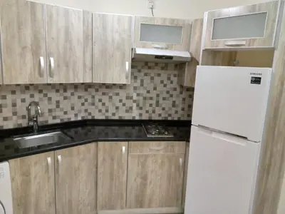 a kitchen with wooden cabinets and a white refrigerator at في ظلال الطبيعه in Aqaba