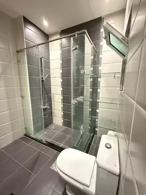 a bathroom with a toilet and a glass shower at Fully Equipped 3BR Apt in Family-Friendly Building in Amman