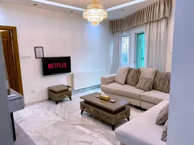 a living room with a couch and a tv at Fully Equipped 3BR Apt in Family-Friendly Building in Amman