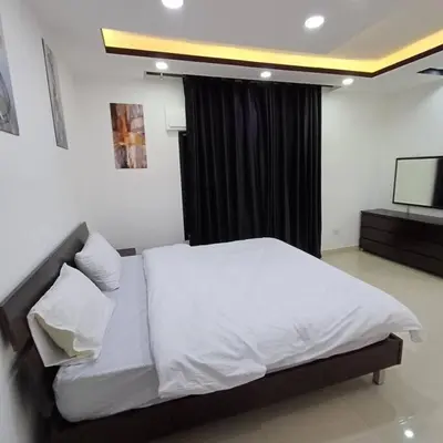 a bedroom with a white bed and a television at Laperla luxury family apartment one in Amman