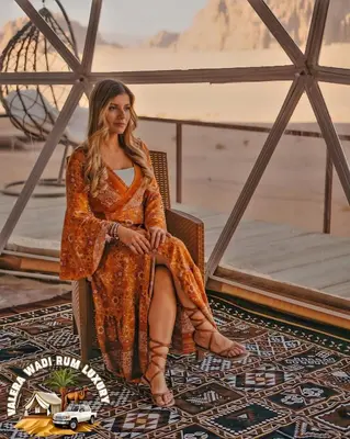 a woman in an orange dress sitting in a chair at Valera wadi rum Luxury in Wadi Rum