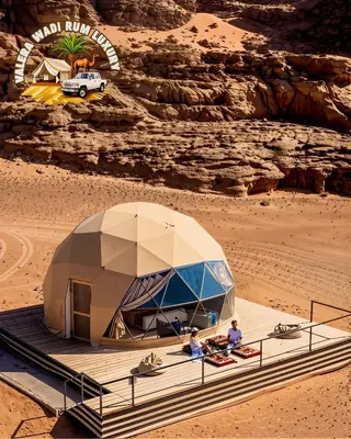 two people sitting in front of a tent in the desert at Valera wadi rum Luxury in Wadi Rum