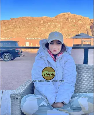 a woman sitting on a bench in a coat at RUM BUBBLES VIEW lUXURY CAMP in Wadi Rum