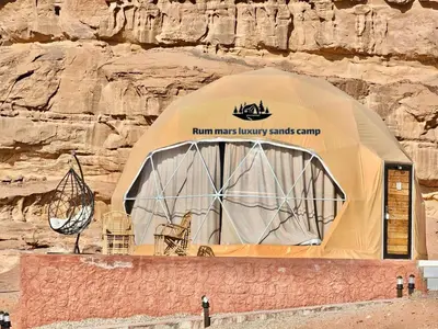 a tent with chairs in front of a rock wall at RUM MARS lUXURY SANDS BUBBLE CAMP in Wadi Rum