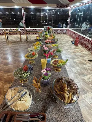 a long table filled with plates of food and flowers at Wadi Rum Camp AW in Disah