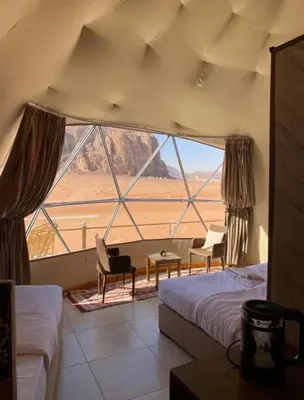 a room with two beds and a large window at Welcome to Wadi Rum in Wadi Rum